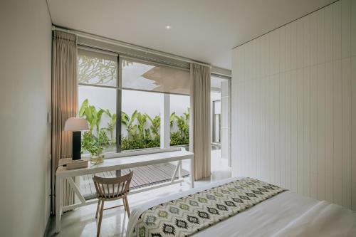 a bedroom with a bed and a desk and a window at Casamaya Villa in Legian