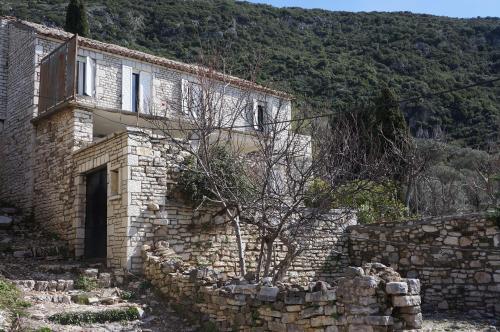 a stone building with a tree in front of it at Les Villas de Qeparo in Qeparo