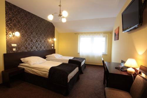 a hotel room with two beds and a television at Hotel Alta in Brzozów