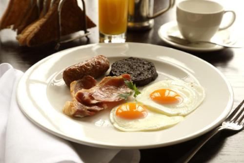 a white plate topped with eggs, sausage and bacon at Macdonald Inchyra Hotel & Spa in Falkirk