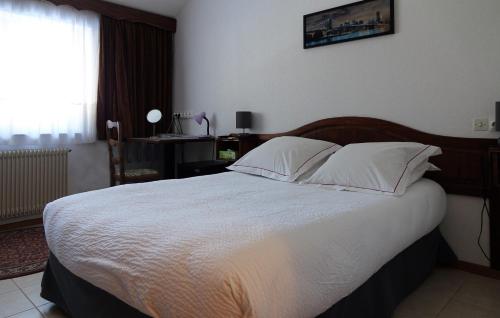 a bedroom with a large bed with white sheets and pillows at Hotel-Spa & Restaurant Logis Domaine Langmatt in Murbach