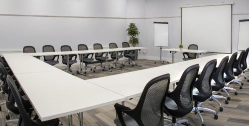 a conference room with white tables and black chairs at De Vere Latimer Estate in Chesham