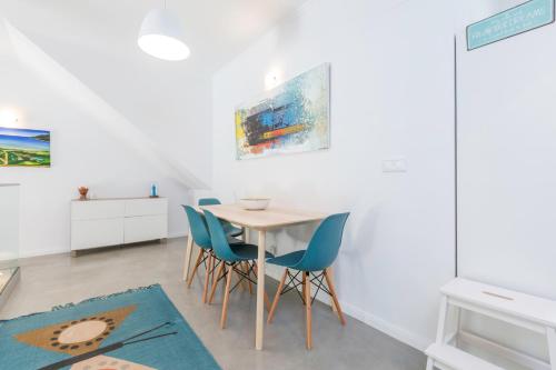 a dining room with a wooden table and blue chairs at Pátio da Rainha A by NOOK in Monte Estoril
