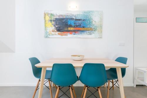 a dining room table with blue chairs and a painting at Pátio da Rainha A by NOOK in Monte Estoril