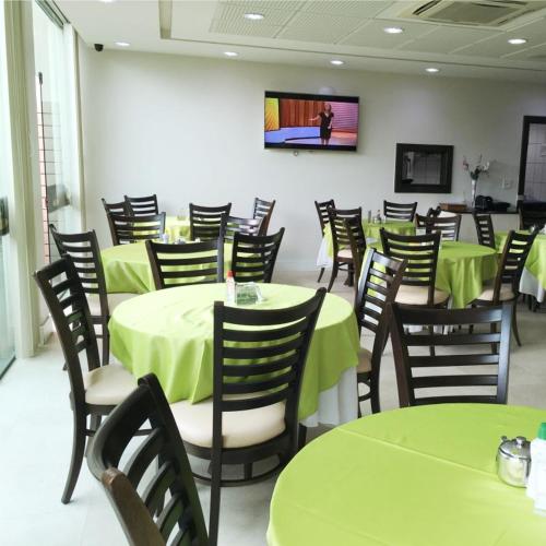 a dining room with green tables and chairs at King Konfort Hotel in Maringá
