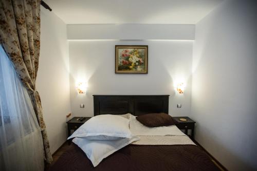 コリビツァにあるPoarta Calimanilorのベッドルーム1室(ベッド1台、ナイトスタンド2台付)、壁に絵が飾られています。