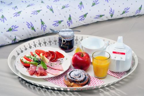 a tray with a plate of food and a glass of orange juice at Viktória Inn Tihany in Tihany