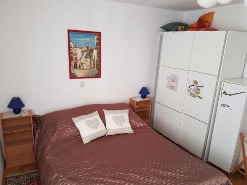 ein Schlafzimmer mit einem Bett und einem weißen Kühlschrank in der Unterkunft Aurora Apartment in Krk
