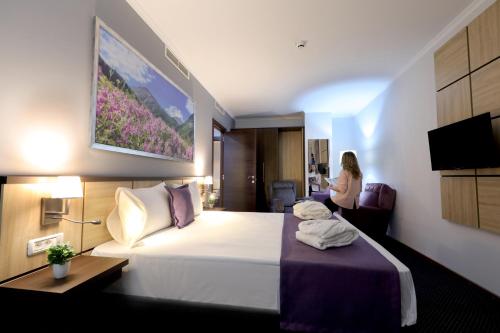 a hotel room with a bed and a woman in a room at Mercure Tetovo in Tetovo
