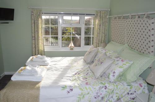um quarto com uma cama com almofadas e uma janela em Bumble Bee Cottage em Hartland