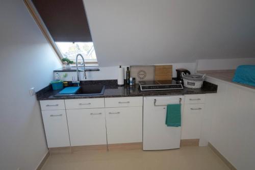 a small kitchen with white cabinets and a sink at Pension / Zimmervermietung Wasbek in Wasbek