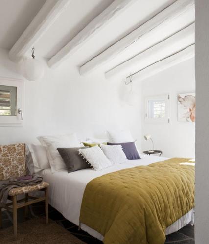 a white bedroom with a large bed with a yellow blanket at Casa Margot in Cadaqués