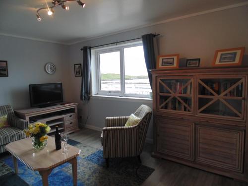 a living room with a large window and a tv at Da Milk Shop Holiday Home in Scalloway