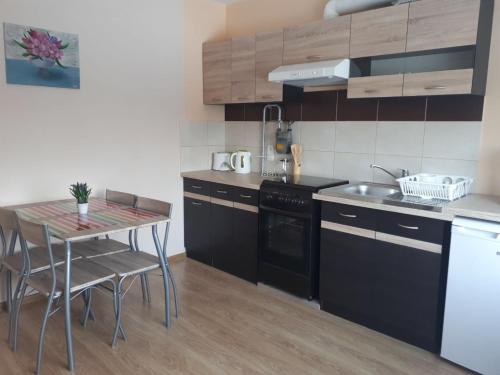 a kitchen with black cabinets and a table with chairs at Ergli Apartment in Ērgļi