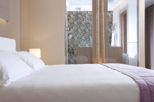 a bedroom with a white bed and a shower at Hotel Aurora in Lido di Jesolo