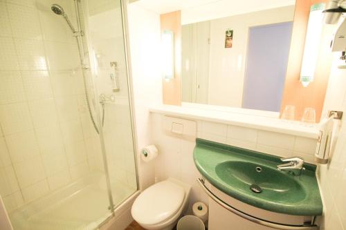 ein Badezimmer mit einem grünen Waschbecken und einer Dusche in der Unterkunft ibis Hotel Düsseldorf Hauptbahnhof in Düsseldorf