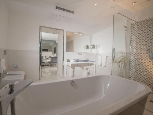 a white bathroom with a tub and a sink at Hotel San Pietro in Naples