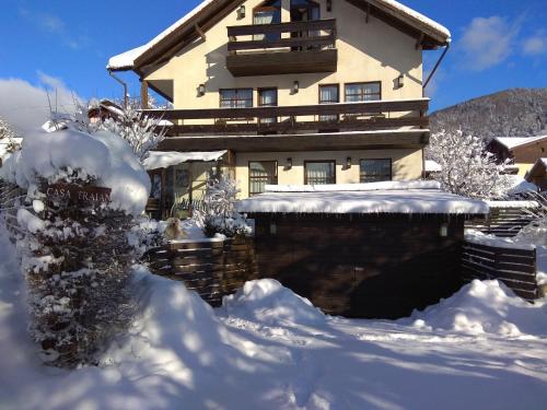 a snow covered house in front of a building at Casa Traian in Sinaia