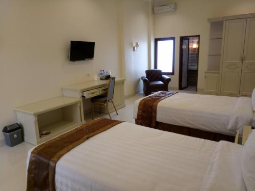 a hotel room with two beds and a desk at Grand Town Hotel Mandai in Makassar