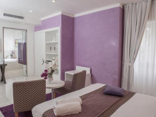 a bedroom with purple walls and a table and chairs at Hotel San Pietro in Naples