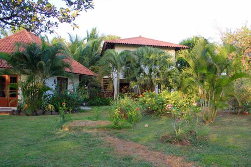 a house with palm trees in front of a yard at Cabañas La Casa de Pucha in Pedasí Town