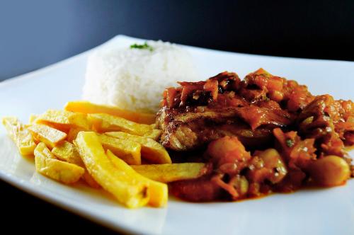 a plate of food with meat and fries and rice at Hotel Castell - Cerca Del Aeropuerto in Guayaquil