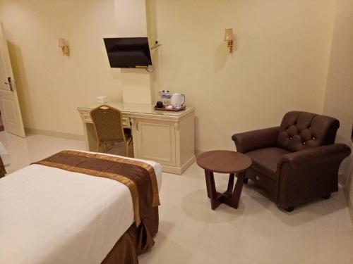 a hotel room with a bed and a chair and a desk at Grand Town Hotel Mandai in Makassar