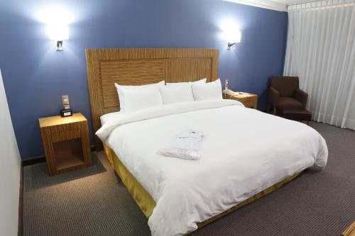a bedroom with a large white bed and a chair at Radisson Hotel & Convention Center Toluca in Toluca