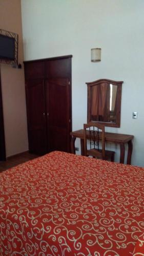 a bedroom with a bed and a chair and a table at Hotel Barroco in Puebla