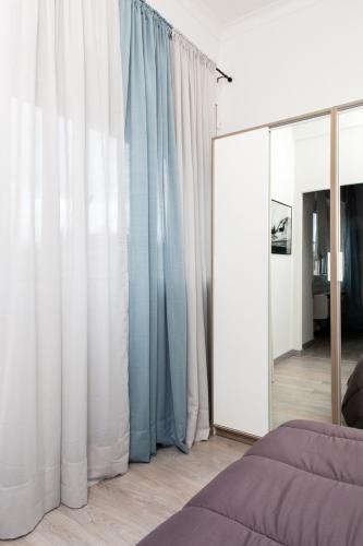 a bedroom with blue curtains and a mirror at Foresteria Boccadasse in Genova