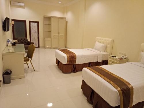 a hotel room with two beds and a desk at Grand Town Hotel Mandai in Makassar