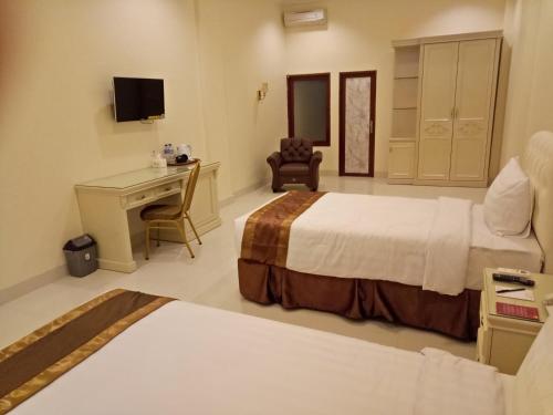 a hotel room with two beds and a desk at Grand Town Hotel Mandai in Makassar