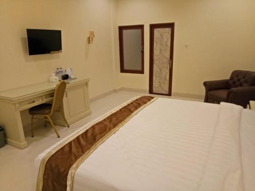 a bedroom with a bed and a desk and a television at Grand Town Hotel Mandai in Makassar