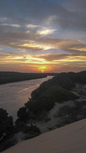 a sunset over a body of water with trees at Canoé Brasil in Praia de Moitas