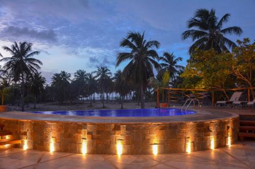 a hot tub with lights on a patio with palm trees at Canoé Brasil in Praia de Moitas