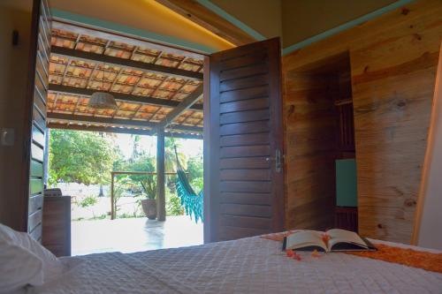 a bedroom with a bed and an open door at Canoé Brasil in Praia de Moitas