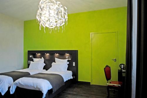 a green bedroom with two beds and a chandelier at Château de Champlong Table Hôtel **** Golf & Spa in Villerest
