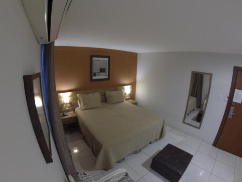 a small bedroom with a bed and a mirror at Serra Negra Pousada Spa in Guarapari