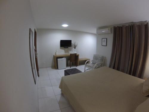 a room with a bed and a desk with a chair at Serra Negra Pousada Spa in Guarapari
