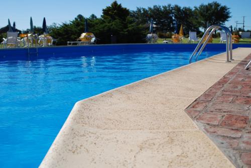 a swimming pool with blue water and a metal stairway at La Campiña Club Hotel & Spa in Santa Rosa