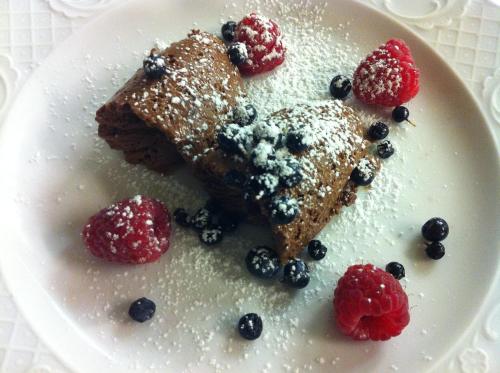 a white plate with two pieces of pancakes and berries at Hotel Reichegger in Villa Ottone