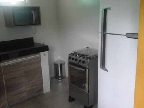 a kitchen with a stove and a refrigerator at Loft Beira Mar Piratininga Niterói RJ in Niterói
