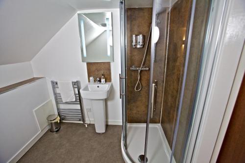 ein Bad mit einer Dusche und einem Waschbecken in der Unterkunft Ferry Inn in Stromness