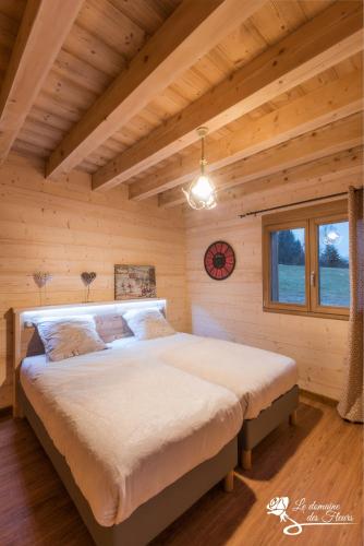 une chambre avec un grand lit dans une pièce en bois dans l'établissement Le Domaine des Fleurs - Chalet La Reine des Prés, à Gérardmer