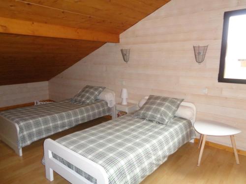 two beds in a room with wooden walls at Le Barail 31 in Couret