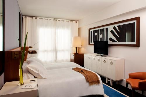 um quarto de hotel com uma cama e uma televisão em Hotel Pulitzer Buenos Aires em Buenos Aires