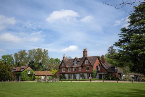 a large red brick house with a grass field at Ravenwood Hall Hotel in Bury Saint Edmunds