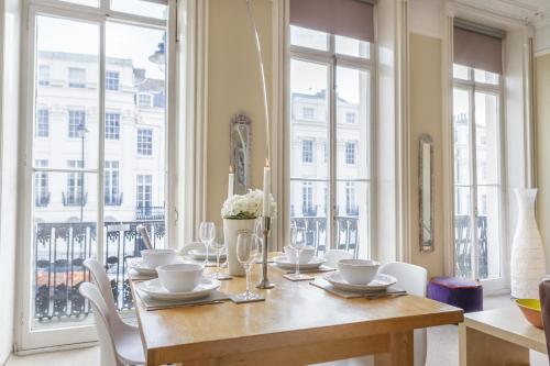 a dining room with a table with chairs and windows at Portland Place in Brighton & Hove