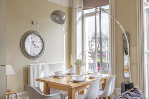 a dining room with a table and a clock on the wall at Portland Place in Brighton & Hove