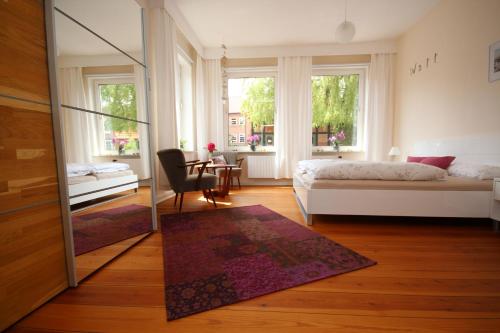 a bedroom with a bed and a table and windows at Haus Gezeiten in Meldorf